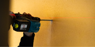 Akkubohrer der mit Hilfe eines Lasers in eine Wand bohrt