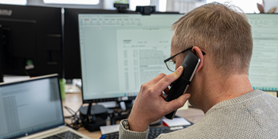 Nahaufnahme von einem Mitarbeiter der am Arbeitsplatz telefoniert.